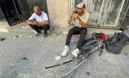 Mamdoh Al Sayed (right) sits on the ground with damaged equipment after being injured on June 27, 2025.