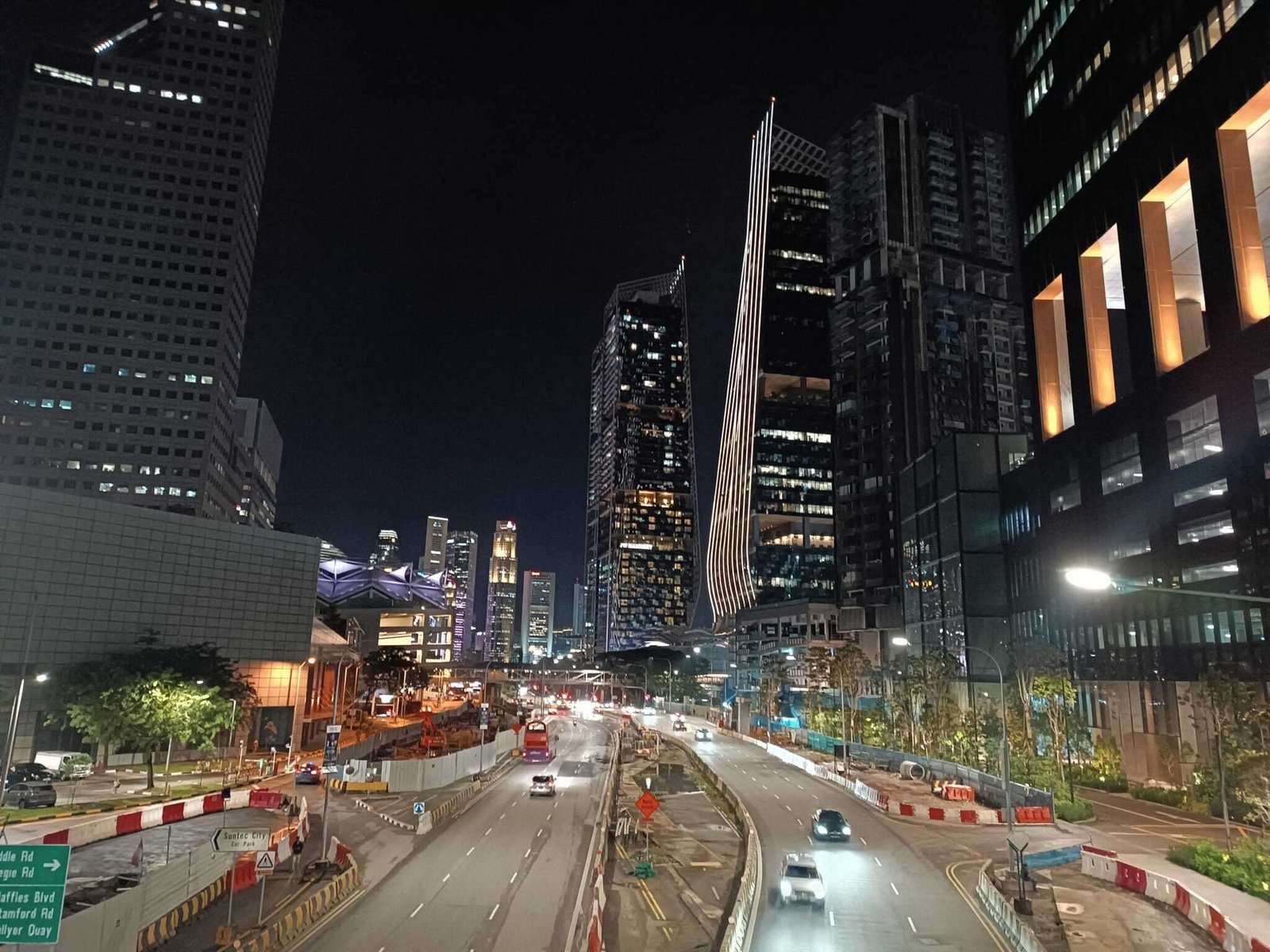 Tall buildings are seen above cars on a roadway at night time