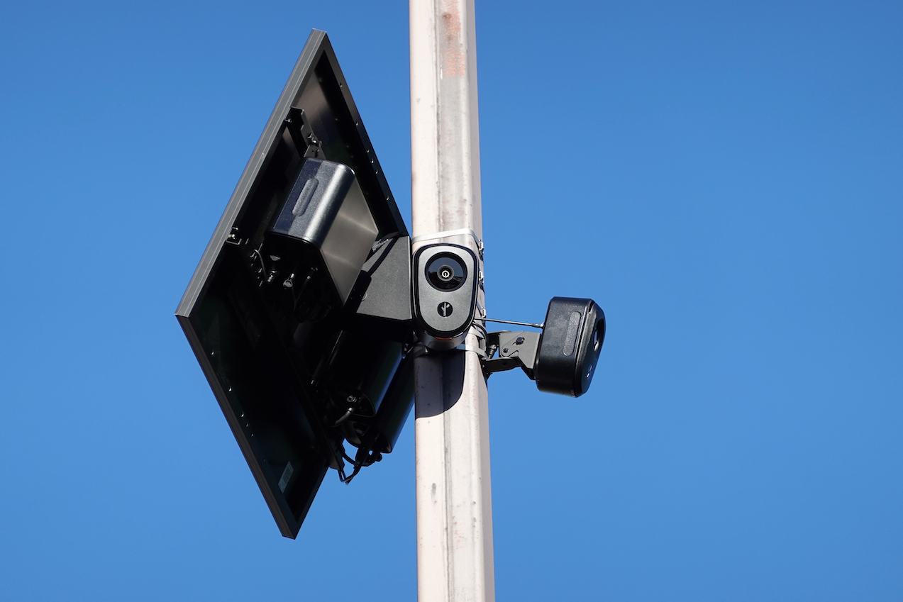 A pair of Flock Safety cameras on a pole, with a solar panel