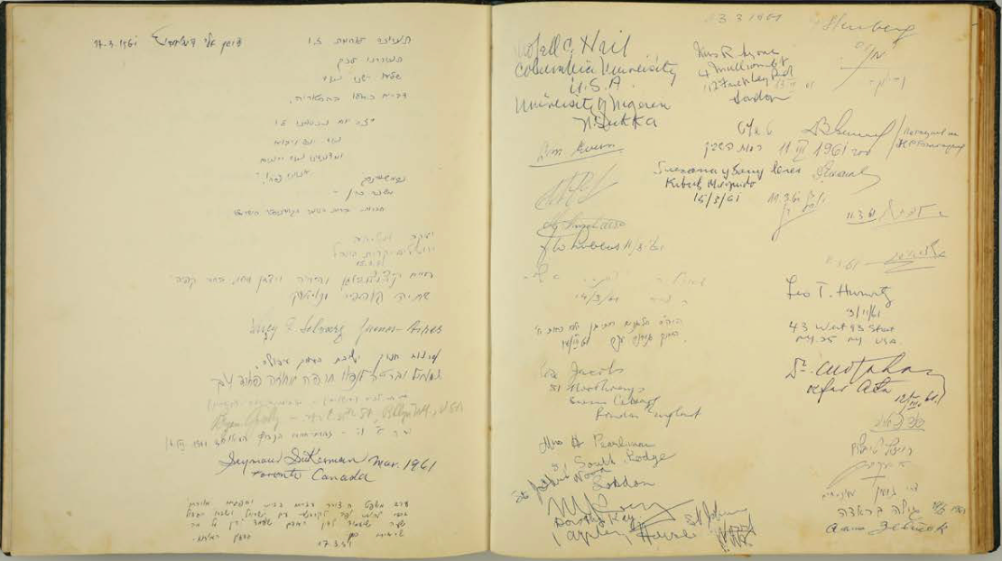 Open visitor book from the Ghetto Fighters’ Museum containing handwritten entries and signatures, including a 1961 inscription by Gideon Hausner, chief prosecutor at the Adolf Eichmann trial.