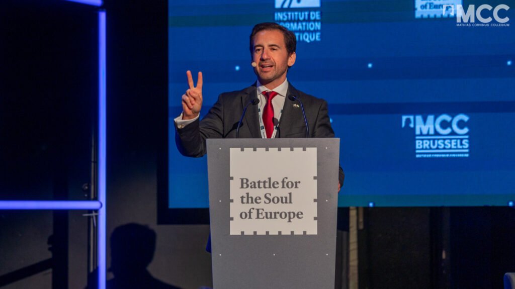 Portuguese politician Pedro Frazão speaks at the Battle for the Soul of Europe conference. Photo: mcc.hu

				
				
				
				
				This article first appeared in the Spring 2026 issue of Index on Censorship, The monster unleashed: How Hungary’s illiberal vision is seducing the Western world, published on 2 April 2026.
Pedro Frazão is a Portuguese far-right politician who fancies himself as something of an orator. At the Battle for the Soul of Europe conference in Brussels last December, the youthful 50-year-old cut a dynamic and sharp-suited figure as he outlined his vision. He called for “patriots” across the continent to fight for its fragile, inherited freedoms. Without the courage to fight, he suggested, the whole edifice of Western civilisation could collapse.
He ended with a flourish: “The West is here and being reborn.” Commenting on his YouTube channel immediately after the conference, Frazão refined his message: “Global elites buy media, hide truths and try to silence those who defend sovereignty, family and national identity. We cannot give in. It is up to us to protect the homeland, the borders and freedom. Portugal needs patriots who will not bow down.”
The conference was organised by MCC Brussels, an offshoot of the Matthias Corvinus Collegium, a Hungarian institution with close links to the country’s prime minister, Viktor Orbán. Politico has described the MCC Brussels as “the EU’s most prominent hard-right pressure group”. Far-right revivalists such as Frazão claim they are fighting for key enlightenment values, including free speech, which they say are under threat from a tsunami of wokery, driven by European Union bureaucrats.
Stars of the Far Right
The line-up at the conference was a Who’s Who of the European far right, including the British academic Matthew Goodwin, who later announced he would be standing for Reform UK in the recent Gorton and Denton parliamentary by-election (which he lost). Goodwin told delegates there was “a political revolution under way”, which would destroy the traditional two-party system in the UK. “We will root out diversity, equality and inclusion policies or woke ideology from taxpayer-funded institutions,” he said, warning that a Reform government would look more like Donald Trump’s second administration in the USA than his first.
Other speakers included Alice Cordier, the French anti-immigration activist and founder of the Collectif Némésis; Patrick Deneen, the prominent conservative author of Why Liberalism Failed; and the Polish Christian philosopher-politician Ryszard Legutko.
The star turn at the Battle for the Soul of Europe was former Czech president Václav Klaus, a key dissident ally of Václav Havel during the Cold War who has tacked further and further to the right in recent years.
MCC was founded in 1996 as a private higher-education institute by the conservative, anti-communist Tombor family and has grown into a hugely influential network of interlinked bodies. Combining the functions of a university, a youth movement and a think-tank, it has also developed a programme of political education under the banner of “talent development”.
MCC Brussels is headed by the Hungarian-British academic Frank Furedi, emeritus professor of sociology at the University of Kent in the UK and a former leader of the Revolutionary Communist Party there. Furedi’s latest book, The War Against the Past: Why the West Must Fight for Its History, is a staunch defence of the legacy of Western values and history against attacks sustained during the culture wars. He sees his role, which he took up two years ago after a chance meeting with the Hungarian prime minister’s political director Balázs Orbán (no relation), as providing a counterbalance to European liberal orthodoxy.
The links to the Fidesz government are explicit, with more than bn of government funds transferred to MCC at the beginning of the 2020s.
Last year, the Brussels arm of the organisation received m from sources allied to Viktor Orbán, according to Politico. Balázs Orbán is its chairman.
Media freedom
In an interview with Index last year, Furedi said: “We are funded by two companies, the oil company MOL and Gedeon Richter, the pharmaceutical company. Now, you could argue that MCC Hungary [the orginal MCC] has got a close association with the government and it empathises with the government’s politics. Our particular organisation is entirely autonomous. That was the condition on which I took the job or set it up…”
Furedi is a staunch supporter of the idea that there is media freedom in Hungary despite Fidesz and its allies owning 80% of media outlets, according to Reporters Without Borders.
He also said: “I do think the attacks on Orbán’s government and Hungary over the free media are misconceived… You have a situation where there are TV channels in Hungary that are anti-government and have a very large viewership. You have a situation where the opposition has got a far greater presence on social media, on social media platforms, than the government has. [If] you go to Budapest and you go to newspaper shops, you’ll find that there are plenty of newspapers, not one, two or three, [that are] hostile and critical to government, so I don’t see it the way it’s represented.”
Since it was established in 2022, MCC Brussels has pumped out a stream of anti-EU reports. In 2025 alone, the think-tank has published 11 substantial reports in an attempt to expose the supposed woke bias of the EU as it wages a war against the free speech of the silent majority. These include Mission Creeps: How EU Funding and Activist NGOs Captured the Gender Agenda, Brussels’s Media Machine: EU Media Funding and the Shaping of Public Discourse, Rule of Lawyers: How the ECHR is Hampering Action on Migration, and Indoctrinating Children: How Brussels Embeds Gender Identity in the Classroom.
The ideological direction of travel is clear, but these reports are not the intemperate ravings of the traditional extreme right. These are detailed arguments honed over the years by the intellectual allies of Furedi as he made his way from the hard left to the populist right.
Europe under threat?
The consistent message at Battle for the Soul of Europe was this: European civilisation is under threat from the combined forces of mass immigration and political correctness. Free speech for people wishing to raise these issues is being stifled. Patriots of sovereign nations need to wake up and fight for the Christian values of the West and come to some kind of understanding with Russia. Just a week after the conference, Trump made it clear that his national security strategy’s Europe policy was based on precisely the same principles.
Writing in Foreign Affairs earlier this year, Nick Cheeseman, Matias Bianchi and Jennifer Cyr identified the concept of The Illiberal International, which brings together far-right politicians to reshape the global order. They identified key gatherings of the far right such as the Make Europe Great Again rally in Madrid in February 2025, hosted by the right-wing party and MCC ally Patriots.EU. The annual Conservative Political Action Conference (CPAC), which met in Hungary in 2022, met again in Budapest on 21 March 2026 – just before parliamentary elections – with Israeli prime minister Benjamin Netanyahu as the keynote speaker. These set-piece events provide a forum for what the Foreign Affairs authors describe as “narrative diffusion”.
December’s Battle for the Soul of Europe was just such an event. The Illiberal International article describes this process brilliantly: “Attendees endorse each other in speeches, cultivate networks of contacts, and share ideas, building international connections that provide visibility and legitimacy for domestic movements. And because these events include both conventional conservative discourse and outright disinformation, they can blur the boundary between the two, making authoritarian messaging appear more palatable to mainstream audiences.”
Viktor Orbán’s concept of “illiberal democracy” has often been cited as an inspiration for the Trump regime, and in recent months the ideological links between Budapest and Washington have become increasingly explicit. At the beginning of February, MCC welcomed an investigation by the USA’s House Judiciary Committee into alleged EU censorship. A statement from MCC Brussels claimed “internal communications from major technology platforms provides incontrovertible proof that the European Union’s regulatory framework is a ‘censorship operating system’ designed to systematically throttle free speech”.
For some time, MCC Brussels has warned of an alliance between unelected EU institutions, tech companies and state-funded NGOs to stifle right-wing political speech. As far as the US committee and the European right are concerned, the EU’s Democracy Shield – an initiative launched in November 2025 by the EU Commission to target disinformation, fake news and foreign interference – is, in fact, a cover for silencing dissent by the liberal orthodoxy.
In response, it launched the Democracy Interference Observatory to counter what it sees as EU interference in elections taking place in sovereign European states. It has announced that its first test case will be April’s Hungarian elections, where it will target EU attempts to identify foreign interference and electoral malpractice.
Truly independent?
The battle lines have been drawn. Opposition candidate Péter Magyar has already warned of Russian interference in the forthcoming election and has urged a stronger EU response. Meanwhile, Magyar’s chief of staff, Márton Hajdu, has called for the application of the EU Digital Services Act to counter disinformation. The latest AI-generated political advert from Viktor Orbán’s party shows a father being executed by a soldier in what looks like German uniform because the EU has dragged Hungary into the war in Ukraine.
Few MCC authors are mainstream academics, and most are referred to as “independent researchers”. The most prolific of these is the Italian journalist and author Thomas Fazi, who writes on EU propaganda and media manipulation. His report on Brussels’s Media Machine is a direct challenge to the EU consensus on disinformation and dissent, arguing that it closes down genuinely alternative voices. He says Brussels funding is used to bolster mainstream media narratives within the EU and, significantly, beyond its borders. His arguments mirror those used by the Trump administration to cut funding to the United States Agency for International Development (USAID) and the United States Agency for Global Media.
“The EU funds media outlets in Ukraine, the Western Balkans, the South Caucasus and Russian/Belarusian exile media. These efforts, under the guise of ‘supporting democracy’, often reflect geopolitical and strategic goals, mirroring methods associated with USAID-style influence campaigns,” he said. Fazi also pushes the MCC Brussels line in mainstream media outlets and is a regular contributor to the British publication UnHerd. Here he is last November on the European Democracy Shield: “[This] is just the latest vision in unfreedom: suppressing dissent and policing speech under the pretext of defending democracy from foreign interference and fake news.”
EU commissioner for democracy, justice and the rule of law Michael McGrath told critics in the European parliament in November: “To those who question the Shield and who say it’s about censorship, what I say to you is that I and my colleagues in the European Commission will be the very first people to defend your right to level robust debate in a public forum.”
The future
Zalán Zubor of the Hungarian investigative non-for-profit publication Atlatszo, has been tracking the activities of MCC for several years. He said there was a common methodology to its work, where it identified freelance writers and paid them yearly grants to undertake unspecified research while writing specific articles adhering to the MCC line.
He explained the forthcoming election was a high-stakes moment for the organisation as Magyar has pledged to set up an agency to prosecute groups that have been the beneficiaries of state largesse. “The MCC is going to be the target,” said Zubor.
The future of MCC Brussels is unclear, but it is possible that it is part of the global strategy of the Hungarian far right in case Viktor Orbán loses the election. For Zubor, this would be an obvious next step for the Hungarian leader. “It is very clear he sees himself as an international figure, the Hungarian leader of the far right.”
While a storm is coming for the MCC and its Brussels branch if Magyar wins the election, the same may be true for independent media if Fidesz returns to power in April. At present, Hungarian citizens can donate 1% of their taxes to civic society groups, including non-profit media organisations such as Atlatszo. The government recently withdrew proposals to make it illegal for these donations to be made to organisations judged “political”, which would have effectively bankrupted independent media. But if Fidesz wins, there is every possibility it will reintroduce the measure.

Hungary and the British Right
The Matthias Corvinus Collegium has funded right-wing propaganda in British universities and paid the salary of Reform politician Matthew Goodwin (left), according to investigations in the UK and Hungary.
Legal campaigners Good Law Project revealed in February that the Roger Scruton Legacy Foundation (RSLF) has received almost 0,000 from MCC since 2023, amounting to 90% of its funding. Directors of the RSLF, set up in honour of the conservative philosopher, include Spectator editor and former Conservative Cabinet minister Michael Gove and Nigel Farage’s senior advisor James Orr. According to its founding documents the foundation is an “international network of institutions and scholars dedicated to furthering the philosophical and cultural achievements of the West”. 
In April 2023, the MCC signed a deal with Sophie Scruton, the widow of Sir Roger Scruton, to provide opportunities for Hungarian students at its “talent centre” to study at Oxford and Cambridge universities. RSLF has since organised conferences at both.
Then, in June last year, the RSLF ran Now & England, a conference in Westminster, which brought together right-wing thinkers and politicians including Rupert Lowe, the Great Yarmouth MP who left Reform to set up his own party, Restore Britain, shortly afterwards and Conservative MP Danny Kruger, who defected to Reform in September 2025. Publicity for the event stated: “England stands at a crossroads. Mass immigration, detached elites, and decaying institutions have strained the country’s sense of identity and direction.”
The connection between RSLF and Hungary was further reinforced when the country’s embassy hosted the Roger Scruton Symposium last October. Right-wing thinkers gathered to celebrate the legacy of the philosopher. They included Goodwin, who stood as the Reform candidate in the recent Gorton and Denton by-election in which he came second to the Green Party.
Goodwin is a “visiting fellow” at the Matthias Corvinus Collegium and spoke at this year’s MCC Feszt, a festival of right-wing thought also addressed by Viktor Orbán and PayPal and Palantir co-founder Peter Thiel. According to leaked documents obtained by the Hungarian investigative reporting site Direkt 36, visiting fellows at MCC are paid between 00 to ,000 per month “plus housing, office space, health insurance and, where appropriate, family support”. The Direkt 36 investigation also revealed the vast sums the MCC spends on events, with .8 million laid out for catering alone. Many of these events take place in the Budapest café in the MCC’s Budapest headquarters. The name of the venue? Café Scruton.

			
			
					
				
				
				
				READ MORE