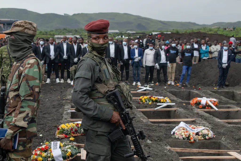 Security force members stand watch as people attend the burial ceremony for victims who died in a drone strike in Masisi Territory in January.