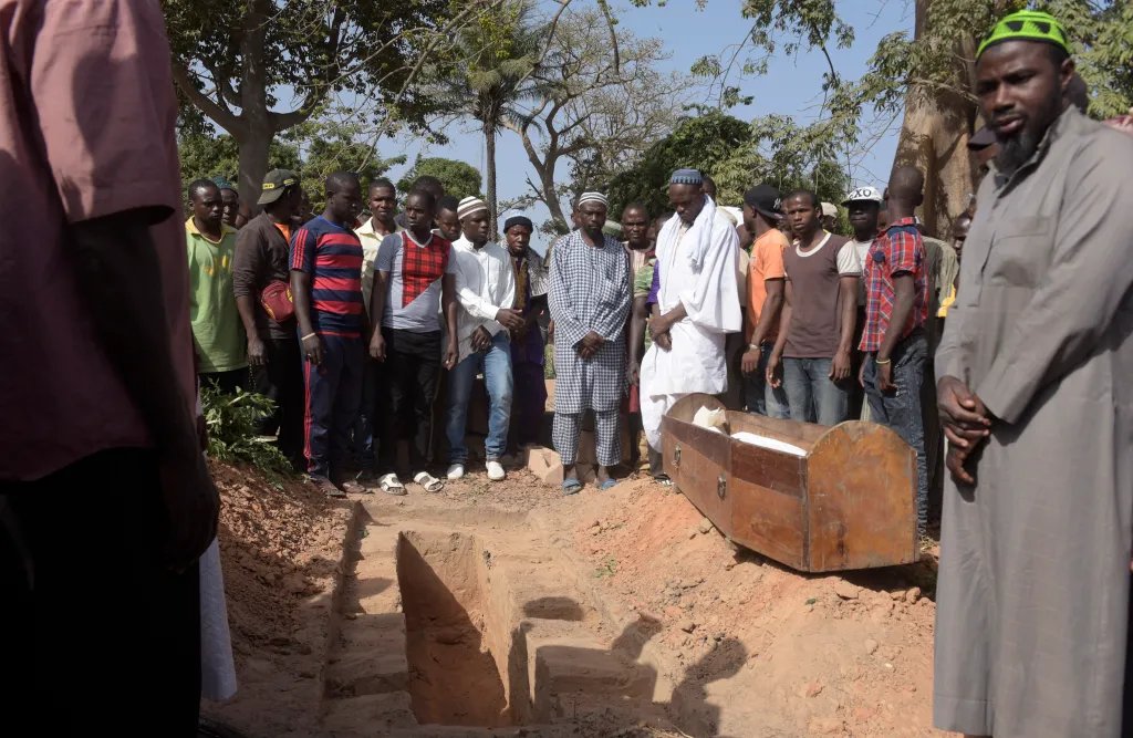 Men pray next to a coffin during a burial in a cemetery in the regional capital Ziguinchor, southern Senegal on January 7, 2018 following an attack by armed men in the Bayotte forest. A ministerial fact-finding mission was headed to Casamance in southern Senegal on January 7, after 13 youths were killed in the first upsurge in violence in the isolated region in years. The youths were collecting wood in the Bayotte forest, 20 kilometres (12 miles) from the regional capital Ziguinchor, "when they were attacked by an armed band of 15 people", army spokesman Abdou Ndiaye told AFP. A source in Ziguinchor said that 13 were killed and two were able to escape, with Ndiaye adding that seven others were injured in the attack. (Photo by SEYLLOU / AFP)