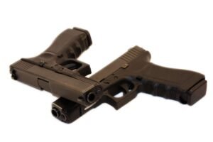Two identical semiautomatic pistols, laid across one another.