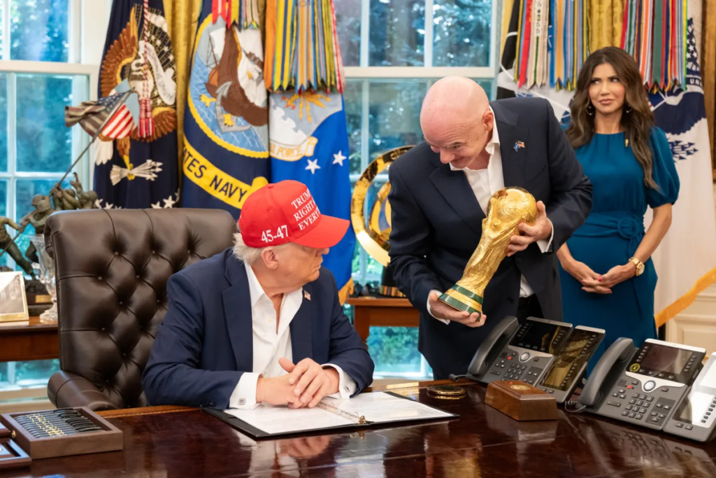 President Donald Trump and FIFA President Gianni Infantino at the White House for the World Cup 2025 draw. Photo: White House

				
				
				
				
				“We don’t live on the moon, we live on planet Earth. We have to respect that we are not kings of the world, who can rule over governments and police forces.”
These were the words of FIFA president Gianni Infantino at a press conference ahead of the World Cup which has started this week. Infantino was responding to criticism of FIFA’s organisation of football’s greatest tournament, which is being held in the USA, Mexico and Canada.
Historically, FIFA has sought to present football as neutral territory, distant from ideological and partisan disputes. The World Cup started out as a symbol of global unity, a celebration of diversity, dialogue between cultures, and football’s ability to bring people together in an increasingly polarised world.
However, neutrality can also be interpreted as a way of silencing certain debates. Whenever the organisation decides to limit the free expression of athletes, fans, or host cities, accusations arise that it is privileging a specific view of what can or cannot be said within the sporting environment.
The World Cup of today is a money-making juggernaut. The 2026 event is likely to see .5 billion pour into FIFA’s coffers and questions over the organisation’s propriety are never far away.
As the tournament begins, a series of events has highlighted a debate that goes far beyond the pitch: to what extent is freedom of expression being respected at the world’s biggest sporting event and how much influence do the host countries have in who can do or say what?
One of the highest profile incidents related to Somali referee Omar Artan. Selected to officiate at the World Cup, Artan would have become the first Somali referee to participate in the tournament. However, he was not allowed entry into the USA by immigration authorities, preventing his participation in the competition. Somalia is one of the many countries on a travel ban list issued by Trump’s government.
The referee’s banning provoked an international reaction and was met with indignation in his country of origin, where the referee was treated as a hero upon his return.
Addressing crowds in Mogadishu on his return, Artan said, “Somalia belongs to all of us. Whether times are good or difficult, I want to tell our youth not to lose hope in our country.”
For many observers, the case symbolised the conflict between the sometimes harsh immigration policies of individual countries and the principles of universality that should guide a global event like the World Cup. While governments have the sovereign right to control their borders, critics argue that preventing the presence of professionals accredited by FIFA itself contradicts the spirit of inclusion that the organisation claims to uphold.
The participation of Iran, at war with the USA, is also proving a tricky challenge for FIFA.
The Iranian Football Federation reported problems involving fans who had bought tickets for World Cup matches but subsequently had their travel permits revoked or faced obstacles entering the host country.
The federation said: “This incident raises serious questions about the influence of non-sporting and political considerations on the organisation of the world’s biggest football event.”
In a tournament presented as a global celebration, the possibility that political and diplomatic factors could interfere with fan attendance has reignited concerns about indirect discrimination.
The issue is not just about the right to watch a match. Modern football is also a space for cultural expression and collective identity. When certain groups face additional barriers to attend the event, it seems the voices of some fans are considered to be worth listening to more than others.
The challenges of running a global event with participation from countries with vastly differing social attitudes is also a prickly problem for FIFA.
Seattle is one of the host cities of the competition and six matches will be played at the city’s main stadium.
As the tournament coincides with Pride month, one of the matches – between Egypt and Iran – has been designated a Pride match.
Seattle’s mayor-elect Kate Wilson wrote on Instagram, “With matches on Juneteenth and Pride, we get to show the world that in Seattle, everyone is welcome…What an incredible honor!”
Iran and Egypt are not quite so impressed. Homosexuality is banned in Iran with LGBTQ+ individuals sometimes facing the death penalty. It is not explicitly banned in Egypt but people are frequently detained and prosecuted under morality laws.
The Egyptian football federation made an official complaint, saying it “categorically rejects the holding of any activities related to supporting homosexuality”. The Iranians chipped in, saying, “It is an unreasonable and illogical thing [for a match between the two teams] to support a specific group.”
The episode laid bare another challenge faced by FIFA in the 21st century: how to reconcile profoundly different cultures, beliefs, and worldviews within the same event? In a globalised environment, what for some represents a legitimate expression of identity may be seen by others as an inappropriate political message. The line separating individual expression and political positioning becomes increasingly difficult to define.
Infantino has tried to shrug off the criticism of these items as well as absurdly high ticket prices (despite which more than six million tickets have been sold).
At the pre-tournament press conference Infantino called on fans to “chill and relax” in face of the problems faced by some. He also stated that he should be given credit for Iran being allowed to participate at all, given the USA is at war with the country.
Infantino’s supporters believe that the leader seeks to prevent external issues from dominating the World Cup narrative, his critics argue that this stance ignores legitimate problems related to rights, inclusion, and transparency.
Interestingly, these controversies contrast with the institutional message promoted by FIFA itself. On several occasions, Infantino has highlighted football’s role as a tool for peace and international dialogue. The organisation frequently emphasises that the sport has the unique ability to unite people regardless of nationality, religion, origin, or political stance. However, recent events demonstrate how complex this mission becomes when confronted with migration policies, diplomatic interests, and cultural disputes.
Another important aspect of the debate involves the press. Major sporting events usually attract journalists from all over the world, responsible not only for covering the matches, but also for investigating social, economic, and political issues related to the tournament. Press freedom organisations warn that access to information and the possibility of reporting on sensitive topics without restrictions are fundamental elements for ensuring transparency. When certain issues generate discomfort for governments or organisers, the risk of indirect pressure on journalistic coverage arises.
The 2026 World Cup demonstrates that discussions about censorship and freedom of expression are no longer limited to the explicit prohibition of speech. Today, they appear in more subtle issues: who is authorised to enter the country, what symbols are allowed in stadiums, what demonstrations are considered acceptable, and what topics can be discussed without generating reprisals.
In a world marked by geopolitical tensions, debates about identity, and security concerns, the promise of a football capable of uniting all peoples is put to the test.
The 2026 World Cup will be remembered for the goals, the misses and the champions. But it may also be remembered as a milestone in an increasingly relevant discussion: how to balance security, diversity, and freedom of expression in a truly global event. The answer to this question may be as important for the future of football as any result achieved on the field.

			
			
					
				
				
				
				READ MORE