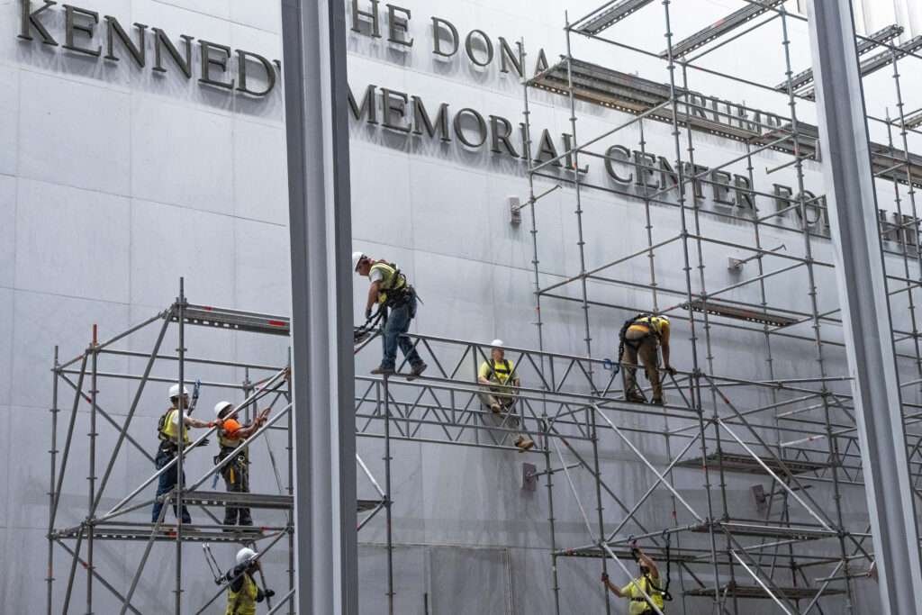 Construction workers build a scaffolding near the sign for the Donald J. Trump and The John F. Kennedy Memorial Center for the Performing Arts in Washington, DC 