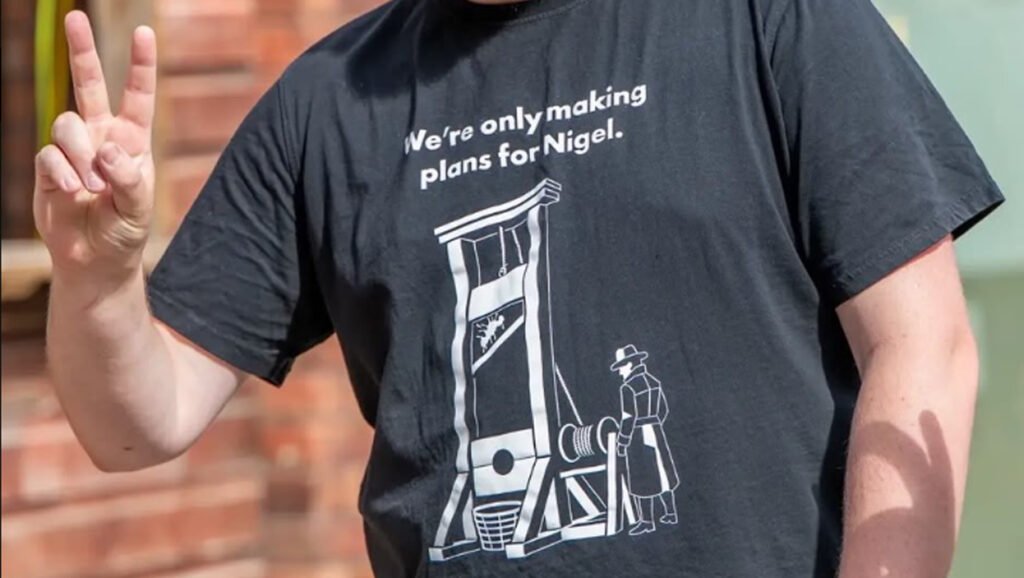 An image showing a person wearing a t-shirt that the Reform party leader has reported to the police for incitement. Photo: X 

				
				
				
				
				Reform UK have complained to police about Green Party leader Zack Polanski for sharing an image on Instagram [which Polanski has since removed] which they claim was an incitement to violence against their leader Nigel Farage. The image is of the slogan “We’re only making plans for Nigel” with the image of a guillotine. The line itself is a reference to the title of a 1979 song by the British band XTC which reached number 12 in the singles chart. While the t-shirt design has no image of Farage nor any branding pertaining to Reform UK, it also bears no reference to the visuals of the song’s sleeve, nor the band’s logo. As with many commercially sold t-shirts, a cultural reference has been repurposed to make its satirical point.
T-shirt slogans are less a call for action, more a proclamation of allegiance. “This machine kills fascists” has the actual word “kill” in it, but is a reference to Woody Guthrie’s motto painted on his guitar (sold by the same company as the “plans” t-shirt, albeit it has since been removed from the website). Wearing the t-shirt is proclaiming an allegiance to the idea of art being used to win the battle for hearts and minds. The appearance of the guillotine in this case is hardly an incitement to imminent action, because a guillotine is an unwieldy weapon for any would-be lone wolf assassin. Were it a noose, gun or knife, that might be a different case. Since the guillotine is not a significant part of British history, we can deduce that here the guillotine serves to express a wish for a revolutionary state in the future (and the wearer’s allegiance to such political change). A future idealised political state of being is far removed from incitement to imminent action.
When demonstrators hold up placards saying “Death to …” or “Kill all … “ that is far closer to incitement. People have gathered en masse in a licensed space for political protest, confident that the camera lenses of mass broadcast outlets will be trained on them. In such a formally constituted space, there can be no doubt about the expressly directed political nature of such signs. A lone individual walking an ordinary high street with “We’re only making plans for Nigel” on his chest may attract citizen lenses, but is not in any formally designated protest space, nor can he be directing his message to any specific audience, as there is no guarantee who will come into his orbit that day.
As an author, I look at the phrase “We’re only making plans for Nigel” and it doesn’t make sense beyond a very specific context. I would never write it, unless there was a group of people from which “we” were only selecting Nigel for some plan, or that “we” wouldn’t even be making plans at all, were it not for Nigel. I would just write “We’re making plans for Nigel” which still retains either meaning, but where the word “only” has become redundant. This is important because it reattaches the phrase back to the XTC song in its specificity. My guess is that XTC simply inserted the word “only” to make the lyrics scan with the musical rhythm. Which makes it a word usage unique to them. Yes, it has been co-opted by the makers of this t-shirt, but to proclaim a specific allegiance, not an incitement to violence.

			
			
					
				
				
				
				READ MORE