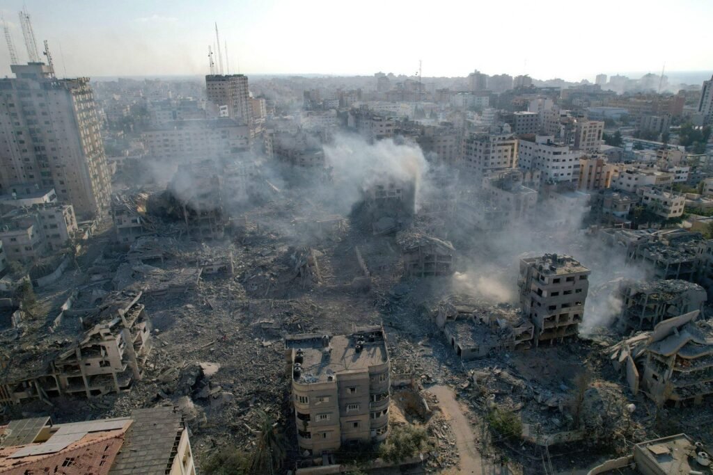 Gaza City in October 2023 (Geopix/Alamy)
If you ask a Palestinian from Gaza where home is, they may well give you a name before they give you an address.
A street. A neighbourhood. A family house. A place where a mother raised her children, where photographs were taken and kept. A place where birthdays were celebrated, where normal and ordinary life unfolded.
Palestinians have carried these places with them for generations, even long after being forced to leave. Sometimes a home is reduced to a key that could be kept for years in hope that one day it might open the door again. A photograph that was hanging on a wall that no longer exists, or an old family album that becomes one of the few physical traces left of a life that was once lived there.
Now, the Israeli government has started to speak about a “migration plan” for Palestinians in Gaza. Leaving, in their words, is being presented as a voluntary choice. But what does “voluntary” mean when the home you have been asked to leave no longer exists?
On September 16, Israel Katz, Israel’s defence minister, announced that in order to “finish the job” in Gaza, the country will begin to implement what he described as a “migration plan”. Earlier this month, Katz said Israel was prepared to facilitate the departure of Palestinians from Gaza by land and sea. Describing the plan as “voluntary”, Katz claimed – without any clear basis for this – that most Palestinians wanted to leave. There are many articles online as proof for this, here are some links for reference:
L’Orient-Le Jour
Times of Israel
Itamar Ben-Gvir, Israel’s minister of public security and a very strong supporter of Netanyahu’s current government, has also proposed a plan to encourage what he describes as the “voluntary emigration” of Palestinians from Gaza. Ben Gvir’s proposal, which includes financial incentives and arrangements with countries that would receive the “emigrants”, sets a target of 1.86 million people leaving Gaza over seven years.
Youmna El Sayed reporting from Gaza City, 7th October (Youmna Al-Sayed)
The language used by Israel’s elected representatives is striking. Migration. Relocation. Evacuation. Voluntary.
These are the words of bureaucracy. They can make the mass movement of millions of people sound organised, almost ordinary. They remove from the equation the noise of a family dragging their bags and belongings through rubble. They exclude from the narrative the child asking where they will sleep that night. They do not show the person returning to their neighbourhood only to find that the house they lived in no longer exists.
Gaza’s population has already experienced repeated displacements. Much of the territory has been destroyed. Three years after the start of Israel’s war, people continue to live in overcrowded or makeshift conditions. In September, just days ago, a damaged building in Gaza collapsed, killing 21 people and trapping others who had been sheltering there because they had no other alternatives. The very next day, another building collapsed, creating another human tragedy.
For these families, leaving is not an abstract political proposal. There is a huge difference between “choosing” to leave one’s home and not having a safe home to return to in the first place.
People migrate every day, and for many reasons. Forced displacement, however, is a different category of movement altogether, carrying with it something else.
Forced displacement carries with it loss, fear, and uncertainty. I know this feeling, because it is how I have been living since I was forced to leave Gaza with my family. Even when the physical place has been destroyed, it does not stop being home.
They remove from the equation the noise of a family dragging their bags and belongings through rubble.
This is why the language matters.
When forced displacement is called “migration”, it creates the understanding of movement between two places of relative choice. When it is called “relocation”, it presents the illusion of people simply being moved from one address to another. When people are told that their departure is “voluntary”, the conditions surrounding that decision are erased from the sentence.
The question is not whether a person physically walks away. The question is what choices remain when staying means living amid ruins, without adequate shelter, safety, or while carrying the fear that another attack could once again put your life and the life of your loved ones in danger? What does it mean to stay when you have no clue whether the life you are trying to hold on to can ever be rebuilt? or the possibility of rebuilding.
And then, there is also the political dimension to the language.
Katz’s latest comments followed months of political discussion in Israel concerning the wish to rid Gaza of its Palestinian population. This notwithstanding, after proposals by Israeli ministers triggered concern, Israeli Foreign Minister Gideon Sa’ar declared on September 9 that the government has no plan to deport Palestinians from Gaza. The United States has also said that at present, there is no US-backed plan to force Palestinians out of Gaza.
These competing statements matter. They show that the political future of Gaza and the question of Palestinian displacement remain contested. But for Palestinians living through the consequences, language from politicians is not separate from reality. Palestinians, after all, have heard the language of displacement before.
In Khanyounis, November 2023 (Youmna Al-Sayed)
In 1948, hundreds of thousands of Palestinians were forcibly displaced from their homes during the war that accompanied the creation of the State of Israel. For Palestinians, the Nakba remains not simply a historical event but a living memory passed from one generation to the next.
That history explains, in part, why words like “migration” and “relocation” carry such weight. Because people remember what happened when leaving became permanent.
But what happens when this language itself begins to shape what the world sees? Censorship is not only about preventing people from speaking. It can also be about the words used to describe what has happened, and the aspects of reality that these words exclude.
A policy can be called a plan. Displacement can be called migration. Being forced out from one’s home can be called voluntary departure. While the words sound neutral, the human experience that is engaged with them is not. And this is what is lost, what is erased, when displacement is discussed in the bureaucratic language of plans and policies. “Home” becomes a random building. “The neighbourhood” becomes an area. “The family” becomes a number. Leaving, being forced to leave, becomes “migration”. And a decision made under conditions that no person should be made to endure becomes “voluntary”.
Even so. People remember their homes long after the buildings have been destroyed. They remember the smell of the kitchen, the view from a window, the neighbour who lived next door, the room where their children slept. These memories cannot be evacuated.
Censorship is not only about preventing people from speaking. It can also be about the words used to describe what has happened
And that’s why the language being used matters so much. If leaving is described as a “choice”, it becomes easier to forget everything that came before it. And so, before accepting the word “voluntary”, a simpler question must be asked:
What choices were left?
If one’s home has been destroyed, if safety is an illusion and if return is uncertain, is leaving really a choice, or simply the last thing left in order to survive?
READ MORE Gaza City in October 2023 (Geopix/Alamy)
If you ask a Palestinian from Gaza where home is, they may well give you a name before they give you an address.
A street. A neighbourhood. A family house. A place where a mother raised her children, where photographs were taken and kept. A place where birthdays were celebrated, where normal and ordinary life unfolded.
Palestinians have carried these places with them for generations, even long after being forced to leave. Sometimes a home is reduced to a key that could be kept for years in hope that one day it might open the door again. A photograph that was hanging on a wall that no longer exists, or an old family album that becomes one of the few physical traces left of a life that was once lived there.
Now, the Israeli government has started to speak about a “migration plan” for Palestinians in Gaza. Leaving, in their words, is being presented as a voluntary choice. But what does “voluntary” mean when the home you have been asked to leave no longer exists?
On September 16, Israel Katz, Israel’s defence minister, announced that in order to “finish the job” in Gaza, the country will begin to implement what he described as a “migration plan”. Earlier this month, Katz said Israel was prepared to facilitate the departure of Palestinians from Gaza by land and sea. Describing the plan as “voluntary”, Katz claimed – without any clear basis for this – that most Palestinians wanted to leave. There are many articles online as proof for this, here are some links for reference:
L’Orient-Le Jour
Times of Israel
Itamar Ben-Gvir, Israel’s minister of public security and a very strong supporter of Netanyahu’s current government, has also proposed a plan to encourage what he describes as the “voluntary emigration” of Palestinians from Gaza. Ben Gvir’s proposal, which includes financial incentives and arrangements with countries that would receive the “emigrants”, sets a target of 1.86 million people leaving Gaza over seven years.
Youmna El Sayed reporting from Gaza City, 7th October (Youmna Al-Sayed)
The language used by Israel’s elected representatives is striking. Migration. Relocation. Evacuation. Voluntary.
These are the words of bureaucracy. They can make the mass movement of millions of people sound organised, almost ordinary. They remove from the equation the noise of a family dragging their bags and belongings through rubble. They exclude from the narrative the child asking where they will sleep that night. They do not show the person returning to their neighbourhood only to find that the house they lived in no longer exists.
Gaza’s population has already experienced repeated displacements. Much of the territory has been destroyed. Three years after the start of Israel’s war, people continue to live in overcrowded or makeshift conditions. In September, just days ago, a damaged building in Gaza collapsed, killing 21 people and trapping others who had been sheltering there because they had no other alternatives. The very next day, another building collapsed, creating another human tragedy.
For these families, leaving is not an abstract political proposal. There is a huge difference between “choosing” to leave one’s home and not having a safe home to return to in the first place.
People migrate every day, and for many reasons. Forced displacement, however, is a different category of movement altogether, carrying with it something else.
Forced displacement carries with it loss, fear, and uncertainty. I know this feeling, because it is how I have been living since I was forced to leave Gaza with my family. Even when the physical place has been destroyed, it does not stop being home.
They remove from the equation the noise of a family dragging their bags and belongings through rubble.
This is why the language matters.
When forced displacement is called “migration”, it creates the understanding of movement between two places of relative choice. When it is called “relocation”, it presents the illusion of people simply being moved from one address to another. When people are told that their departure is “voluntary”, the conditions surrounding that decision are erased from the sentence.
The question is not whether a person physically walks away. The question is what choices remain when staying means living amid ruins, without adequate shelter, safety, or while carrying the fear that another attack could once again put your life and the life of your loved ones in danger? What does it mean to stay when you have no clue whether the life you are trying to hold on to can ever be rebuilt? or the possibility of rebuilding.
And then, there is also the political dimension to the language.
Katz’s latest comments followed months of political discussion in Israel concerning the wish to rid Gaza of its Palestinian population. This notwithstanding, after proposals by Israeli ministers triggered concern, Israeli Foreign Minister Gideon Sa’ar declared on September 9 that the government has no plan to deport Palestinians from Gaza. The United States has also said that at present, there is no US-backed plan to force Palestinians out of Gaza.
These competing statements matter. They show that the political future of Gaza and the question of Palestinian displacement remain contested. But for Palestinians living through the consequences, language from politicians is not separate from reality. Palestinians, after all, have heard the language of displacement before.
In Khanyounis, November 2023 (Youmna Al-Sayed)
In 1948, hundreds of thousands of Palestinians were forcibly displaced from their homes during the war that accompanied the creation of the State of Israel. For Palestinians, the Nakba remains not simply a historical event but a living memory passed from one generation to the next.
That history explains, in part, why words like “migration” and “relocation” carry such weight. Because people remember what happened when leaving became permanent.
But what happens when this language itself begins to shape what the world sees? Censorship is not only about preventing people from speaking. It can also be about the words used to describe what has happened, and the aspects of reality that these words exclude.
A policy can be called a plan. Displacement can be called migration. Being forced out from one’s home can be called voluntary departure. While the words sound neutral, the human experience that is engaged with them is not. And this is what is lost, what is erased, when displacement is discussed in the bureaucratic language of plans and policies. “Home” becomes a random building. “The neighbourhood” becomes an area. “The family” becomes a number. Leaving, being forced to leave, becomes “migration”. And a decision made under conditions that no person should be made to endure becomes “voluntary”.
Even so. People remember their homes long after the buildings have been destroyed. They remember the smell of the kitchen, the view from a window, the neighbour who lived next door, the room where their children slept. These memories cannot be evacuated.
Censorship is not only about preventing people from speaking. It can also be about the words used to describe what has happened
And that’s why the language being used matters so much. If leaving is described as a “choice”, it becomes easier to forget everything that came before it. And so, before accepting the word “voluntary”, a simpler question must be asked:
What choices were left?
If one’s home has been destroyed, if safety is an illusion and if return is uncertain, is leaving really a choice, or simply the last thing left in order to survive?
READ MORE